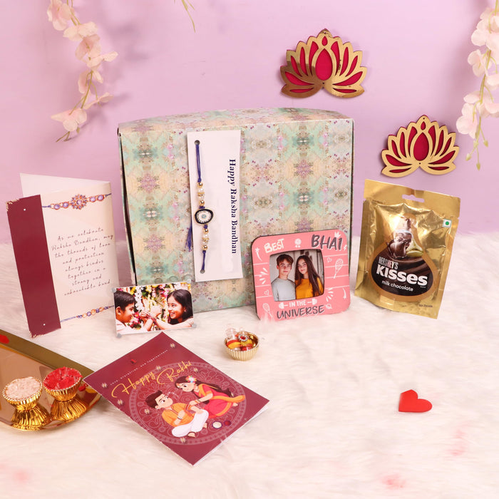 Art Street Rakshabandhan Gift Hamper with Sweets for Brother and Bhabhi, Megantice and acrylic photo frame, Evil Eye Rakhi with Chawal and Roli Gift Set for Celebrate Raksha Bandhan (Pack of 7 Items)